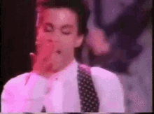 a man in a white shirt and polka dot tie is smoking a cigarette .