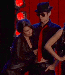 a man in a top hat and tie is hugging a woman in a black jacket
