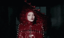 a woman in a red costume with spikes on her head .