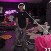 a man wearing headphones is dancing in a room with a neon sign that says ' safari '