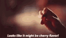 a person is holding a cherry in their hand .