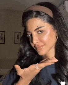a woman wearing a headband and a ring is making a funny face