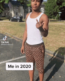 a man in a tank top and shorts is giving the middle finger .