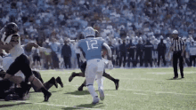a football player wearing the number 12 jersey is running on the field