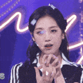 a woman wearing a headband with the letter s on it stands in front of a purple background
