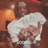 a man is holding a bunch of money in his hands and the word sodmg is on the bottom