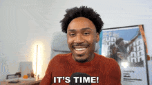a man says it 's time in front of a poster