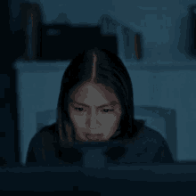 a woman is sitting in front of a computer screen at night .