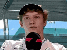 a young man wearing a mercedes shirt holds a microphone