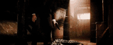 a man in a suit is standing next to a zebra laying on the floor in a dark room .