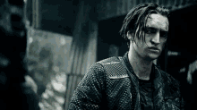 a man with dreadlocks is wearing a black leather jacket and looking at the camera .