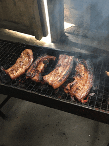 ribs are cooking on a grill with smoke coming out of it