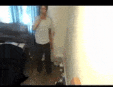 a man in a white shirt and black pants is standing in a bedroom .