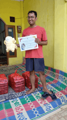 a man in a red shirt is holding a certificate and a stuffed sheep