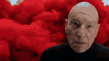 a bald man is standing in front of a red background .