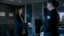 a woman in a police uniform is talking to another woman in front of a corner services logo .
