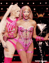 a woman in a pink outfit is standing next to a man in a black jacket