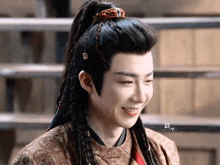 a young man with long hair and braids is smiling .