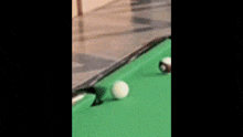 a person is playing pool with a cue and a ball on a green table