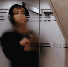 a blurred image of a person standing in front of a glass door .
