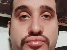 a man with a mustache is making a face in front of a sign that says aranc ny05