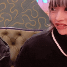 a girl with a piercing in her lip is sitting on a green couch