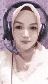 a woman wearing a hijab and headphones is smiling .