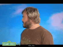 a man with a beard is standing in front of a sesame street logo