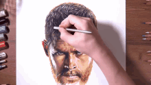 a person is drawing a bearded man 's face with a pencil
