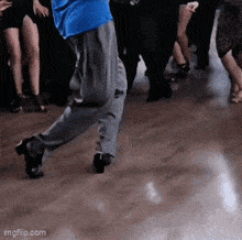 a man in a blue shirt is dancing on a wooden floor with other people .