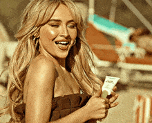 a woman in a bikini is holding a tube of l' oreal sunscreen