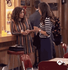 a woman in a striped dress talks to another woman in front of a sign that says " telephone police "