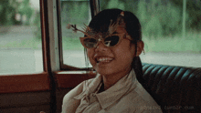 a girl wearing sunglasses is smiling in a photo taken by p3ns1v3