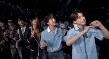 a group of young men are dancing on a stage in a crowd .