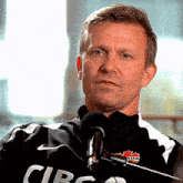 a man wearing a black and white shirt with the word circ on it stands in front of a microphone