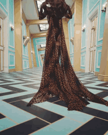 a woman in a long leopard print dress is standing in a hallway