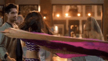 a man and a woman are dancing together in a room with a purple cloth .