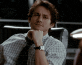 a man in a plaid shirt and tie is wearing a watch