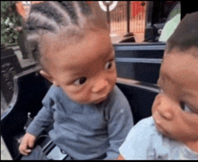 two babies are sitting next to each other and looking at the camera