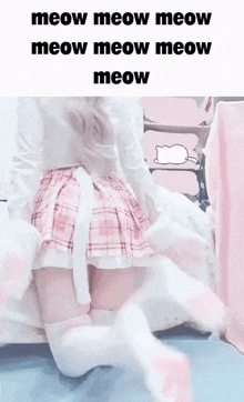 a girl in a pink plaid skirt and white socks is kneeling on a bed .