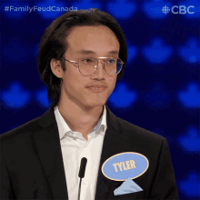 a man in a suit and glasses has a name tag that says tyler