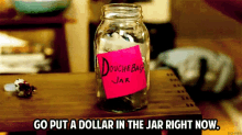 a mason jar with a pink sticky note that says douchebag jar