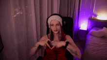 a woman wearing headphones and a santa hat makes a heart with her hands