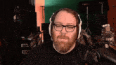 a man with a beard and glasses is wearing headphones and smiling