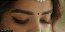a close up of a woman 's eye with a red dot on the forehead