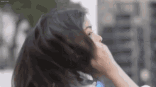 a close up of a woman 's face with her hand on her hair .