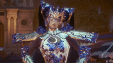 a woman is wearing a blue and gold costume with a crescent moon on her chest