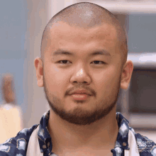 a man with a shaved head and a beard is wearing a shirt that says the great british baking show