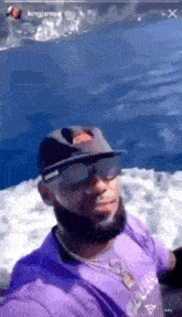 a man wearing a purple shirt and a hat is taking a selfie