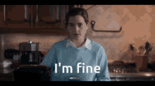 a woman in a blue sweater says i 'm fine while holding a cup of coffee